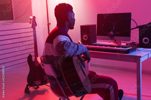 Create music and a recording studio concept - african american man guitarist recording electric guitar track in home studio