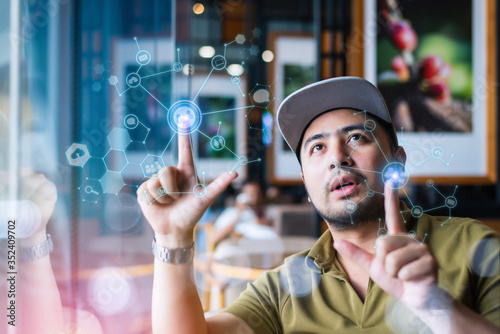 Young man working with virtual screen, navigating and changing positions of icons on futuristic technology display with fingers, looking at the panel absorbedly with excitement photo