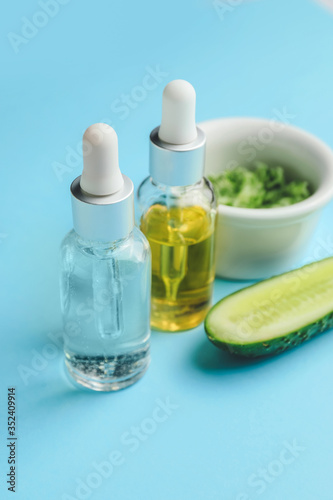 Fototapeta Naklejka Na Ścianę i Meble -  Bottles of essential oil and cucumber on color background