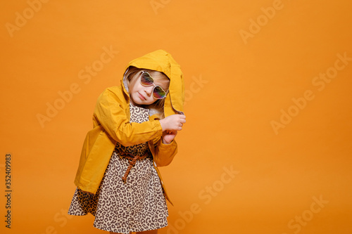 funny girl in yellow raincoat with rabbit ears on yellow background