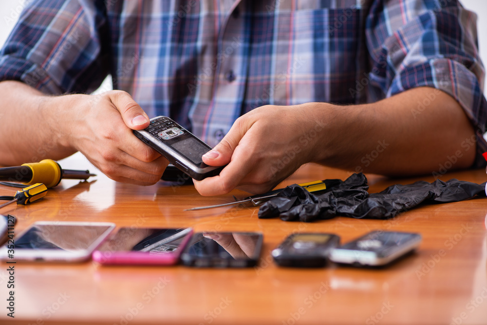 Fototapeta premium Young male technician repairing mobile phone
