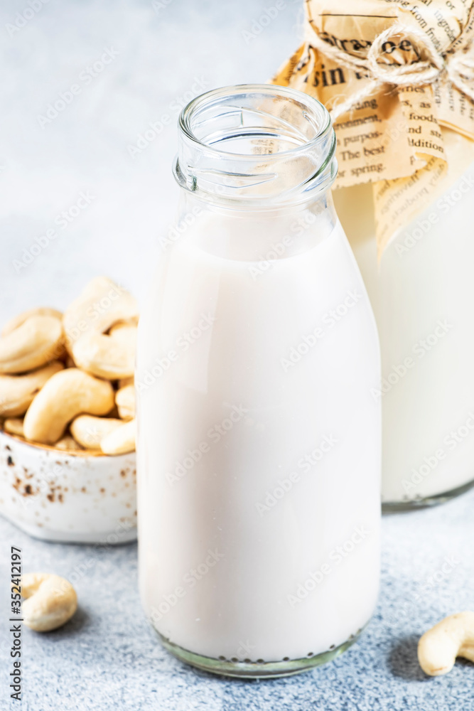 Vegan Cashew nut milk in bottles, closeup, white table background. Non dairy alternative milk. Healthy vegetarian food and drink concept. Copy space Vegan Cashew nut milk in bottles, closeup, white table background. Non dairy alternative milk. Healthy vegetarian food and drink concept. Copy space