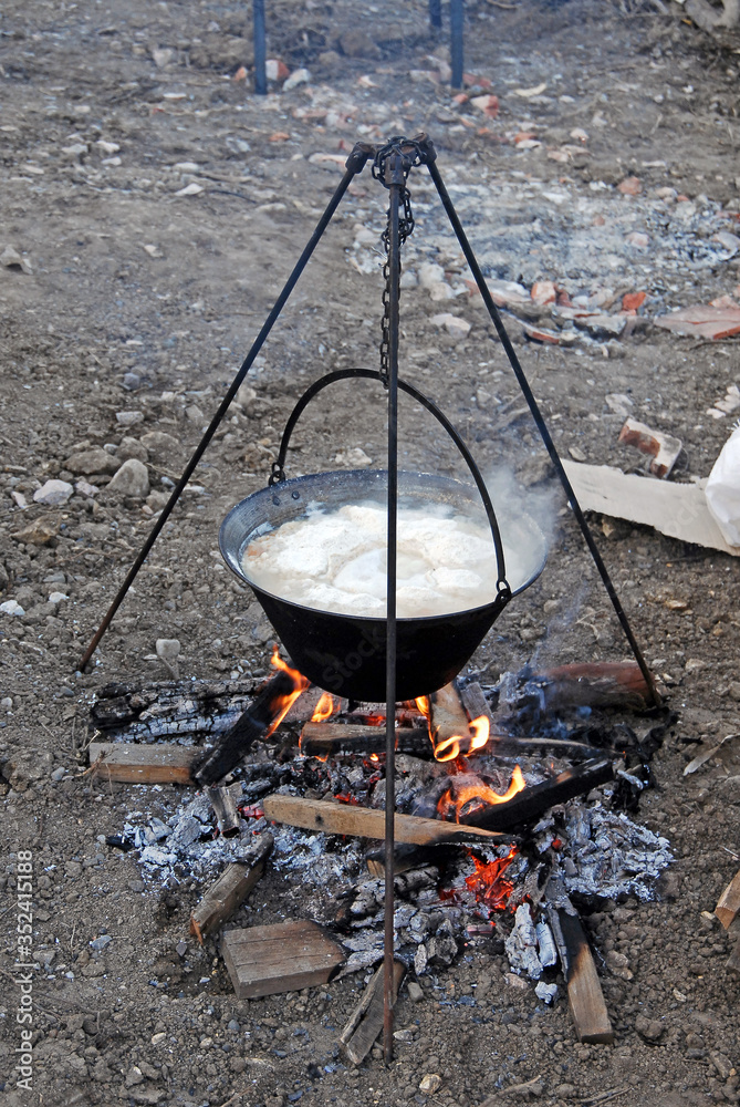 The soup in the cauldron is simmering on the fire.
The cauldron hangs from a tripod. The soup in the cauldron is simmering on the fire.
The cauldron hangs from a tripod.