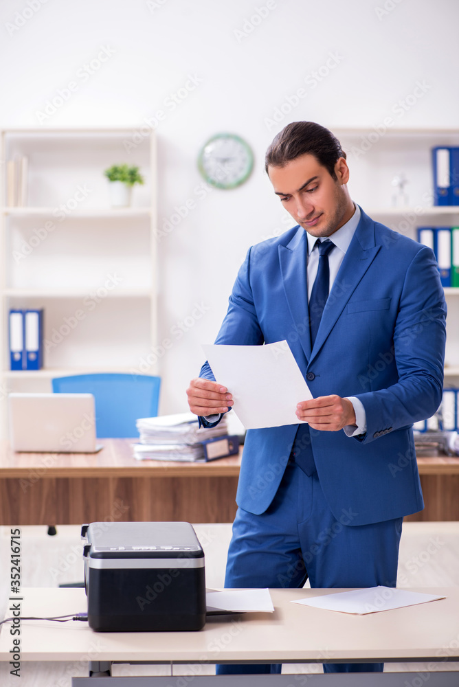 Young male employee making copies at copying machine Young male employee making copies at copying machine