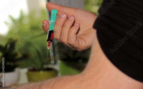 A man injecting himself with a syringe filled with red liquid