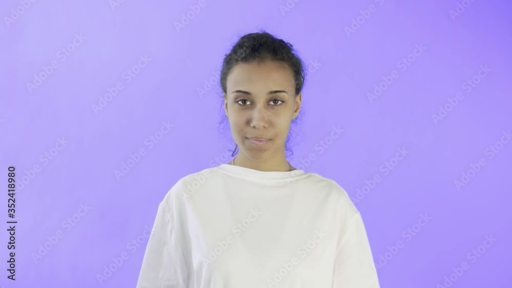 CuteAfro-American Girl is showing ok with two thumbs and smiling on Violet Background in Studio CuteAfro-American Girl is showing ok with two thumbs and smiling on Violet Background in Studio