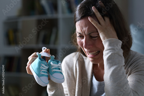 Sad mother missing her daughter after miscarriage at night at home photo