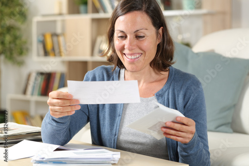 Happy middle age woman opening receipts at home
