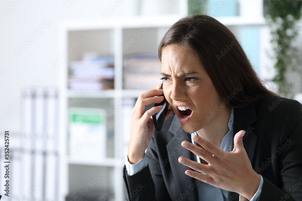 Angry executive arguing calling on phone at office Angry executive arguing calling on phone at office