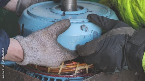 skilled man hands in gloves assemble winch motor after repair on industrial Natig Aliev oil tanker extreme close view photo