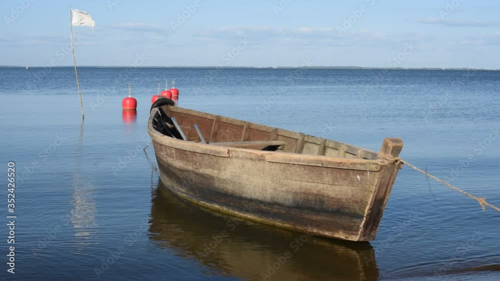 Small wooden boat floating on the clear water of a natural lake, HD video Small wooden boat floating on the clear water of a natural lake, HD video