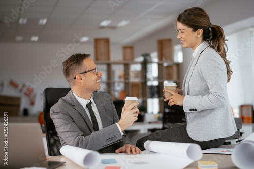 Colleagues in office. Businesswoman and businessman drinking coffee in office. 