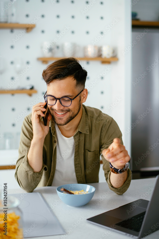 Young man eating breakfast andto the phone. Handsome man enjoying at home. Young man eating breakfast andto the phone. Handsome man enjoying at home.