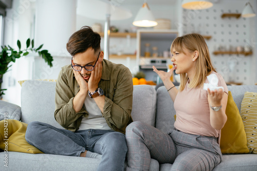 Husband and wife are arguing on the couch. Angry wife is yelling at her husband.. 