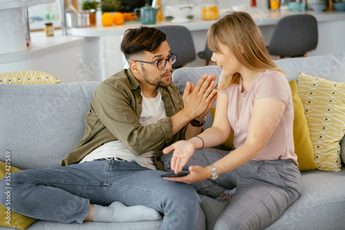 Husband and wife are arguing on the couch. Angry wife is yelling at her husband.. 