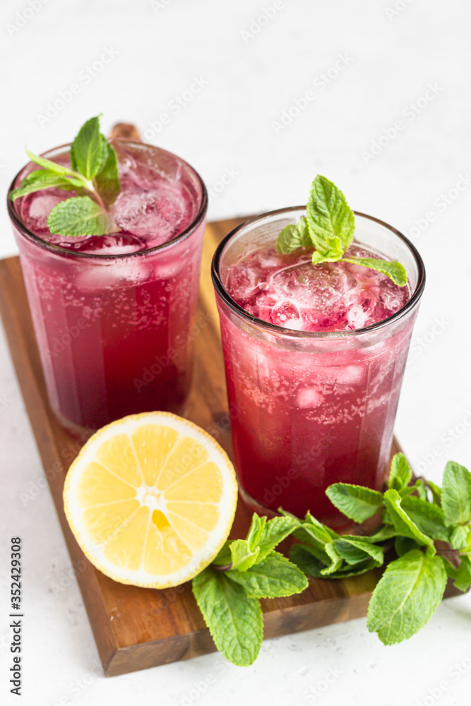 Sparkling pink lemonade with lemon and mint on light grey concrete background. Sparkling pink lemonade with lemon and mint on light grey concrete background.