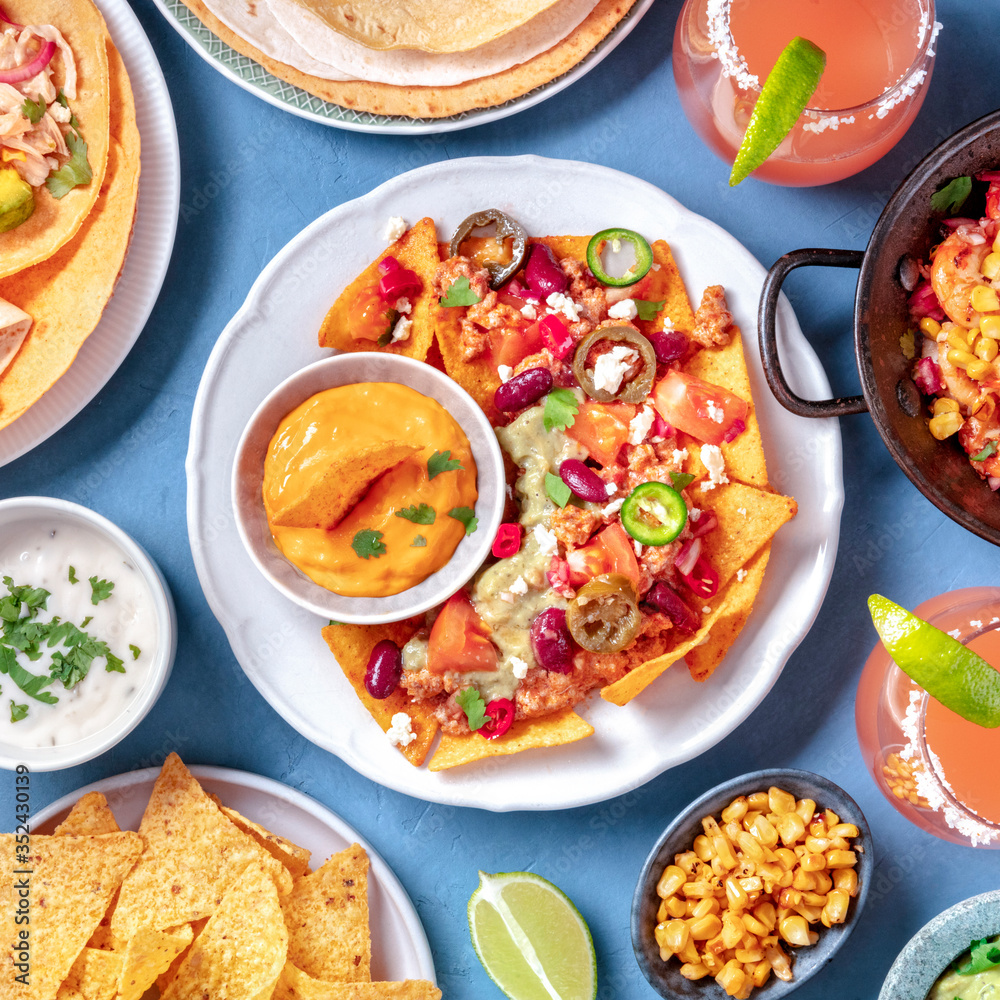 Mexican food, a flat lay. Nachos, tortillas, Paloma cocktails and other dishes, overhead square shot