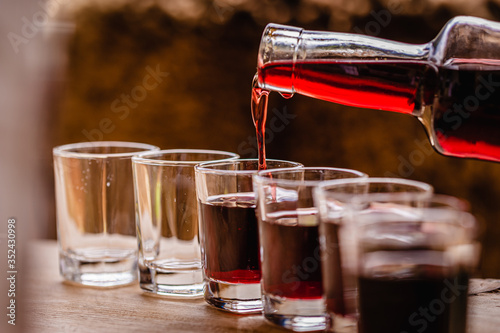 Foto pouring red alcohol shots in small glasses on a celebration