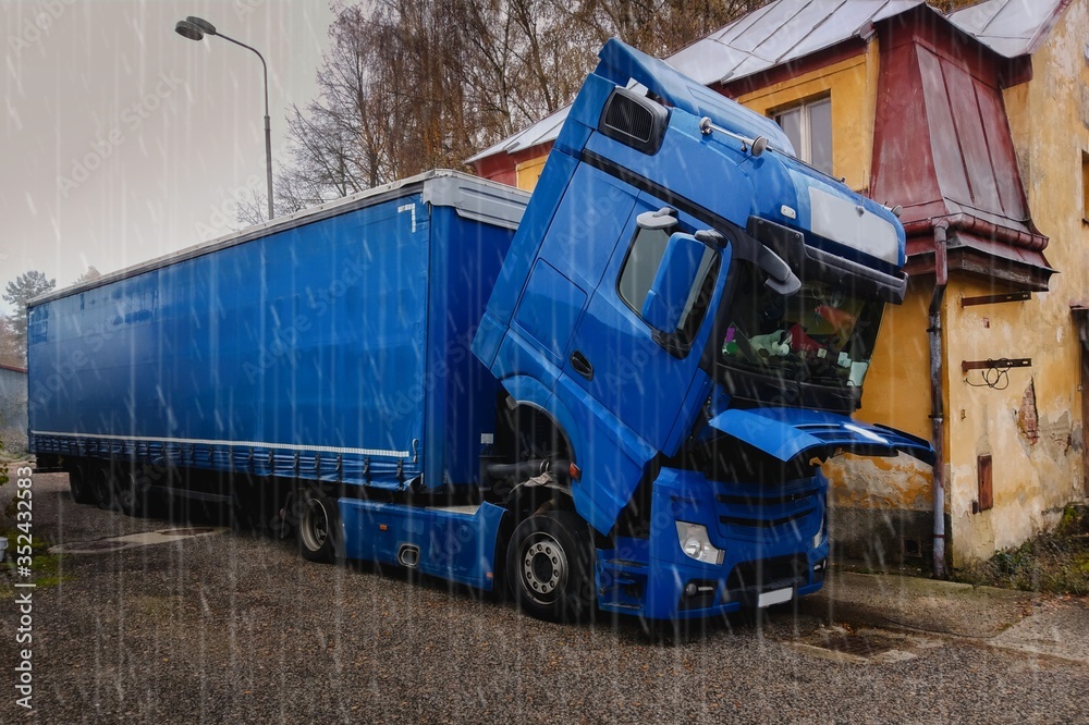 A broken truck, with the cab lowered, is waiting for a repair car service.It`s rainy.Broken truck next to the old house. Traffic complications. A broken truck, with the cab lowered, is waiting for a repair car service.It`s rainy.Broken truck next to the old house. Traffic complications.