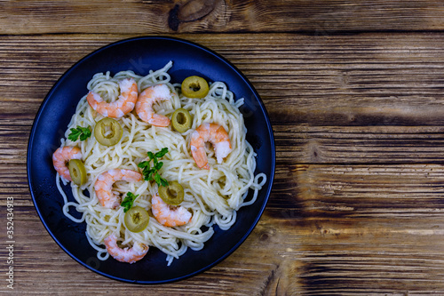 Italian pasta with shrimps and olives in a black plate. Top view