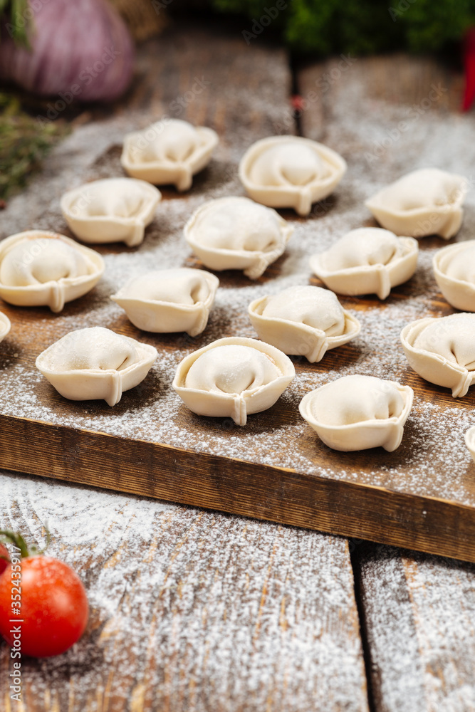 Semi-finished pelmeni dumplings on wooden board