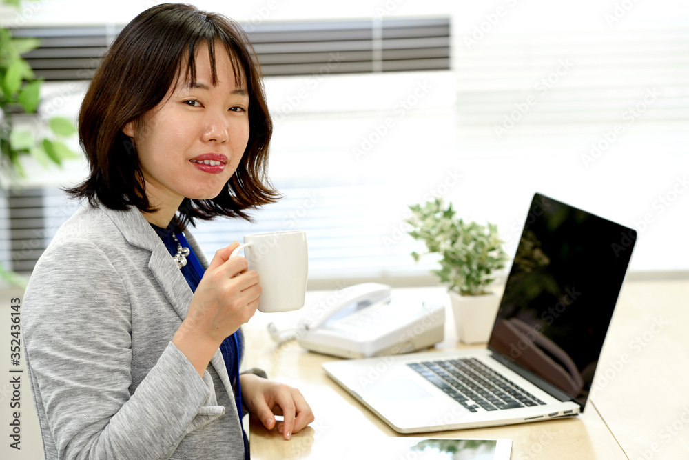 飲み物を飲みながらPCを操作する女性 飲み物を飲みながらPCを操作する女性