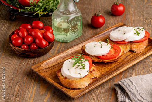 mozzarella with tomato slice on the toast on wooden board