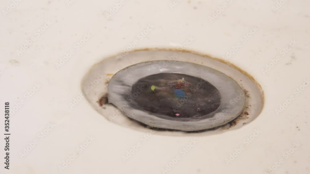 Side view, close up. Bath clogging concept. Water drain is clogged with hair. Side view, close up. Bath clogging concept. Water drain is clogged with hair.