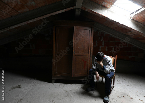 depressed and pensive lonely person sitting in a attic