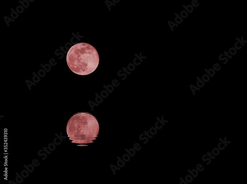 full Red moon and the reflection on the water of the sea