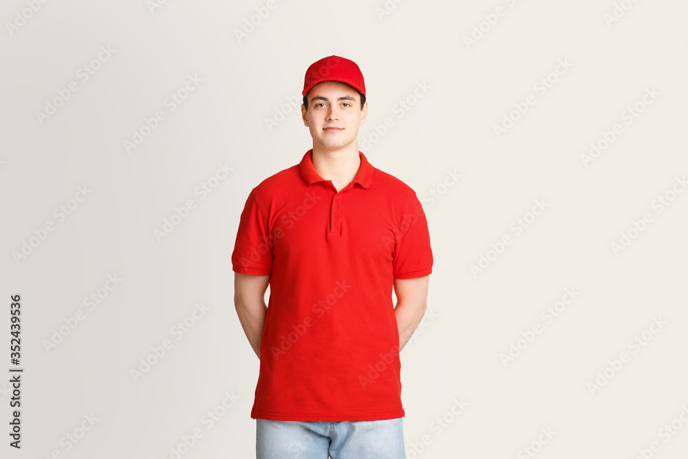 Modern post and package delivery. Courier in red uniform on light background Modern post and package delivery. Courier in red uniform on light background