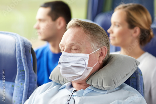 tourism, healthcare and pandemic concept - senior man wearing face protective medical mask for protection from virus disease sleeping in travel bus with neck pillow
