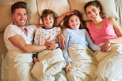 Glückliche Familie mit zwei Kindern im Bett photo