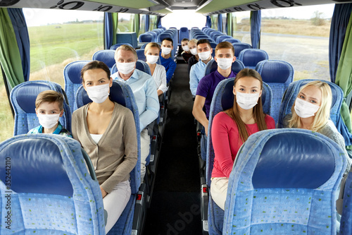 tourism, healthcare and pandemic concept - group of passengers wearing face protective medical mask for protection from virus disease in travel bus