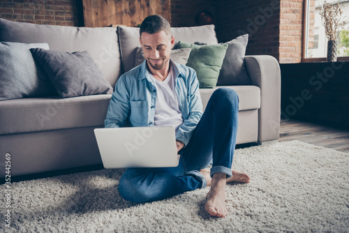 Принти на полотні Photo of handsome homey guy relaxing sitting comfy fluffy carpet near couch brow