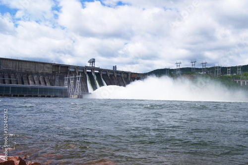 spillway on a dam which is in the mountains, streams of water with spray fly down into the river. hydroelectric power generation