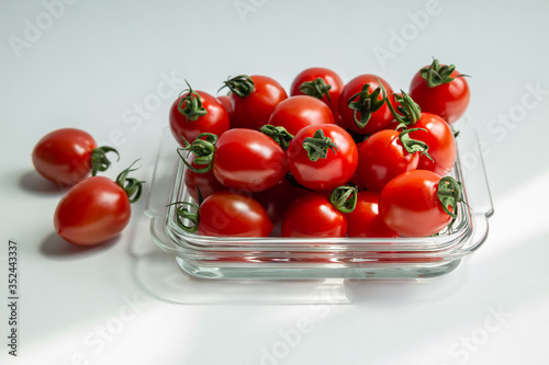 Fresh red cherry tomato in square transparent glass.