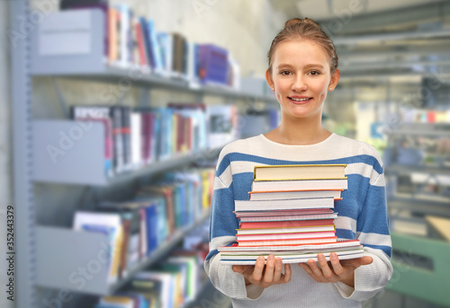 education, school and learning concept - happy smiling teenage student girl with books over library background