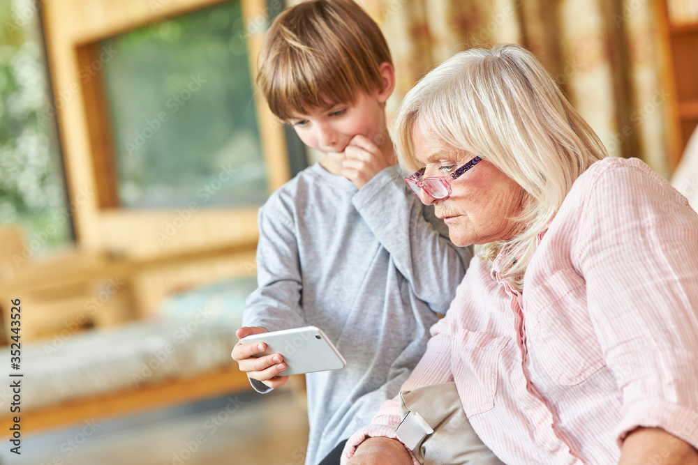 Großmutter und Enkelsohn lesen gemeinsam eine SMS