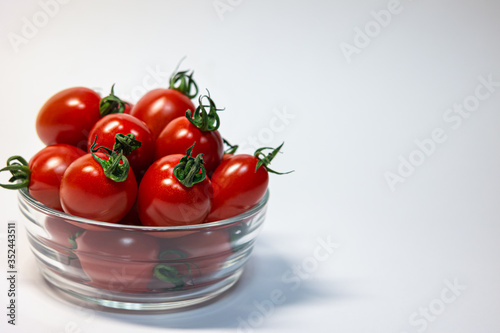fresh red cherry tomato in round transparent glass and copy space