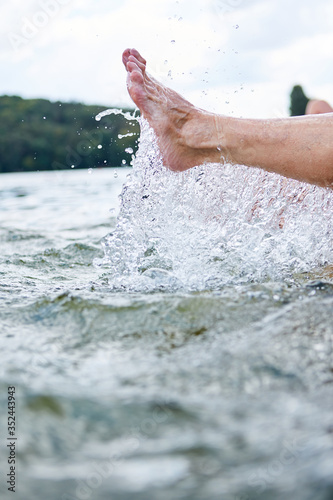 Bare feet in the lake splash with water