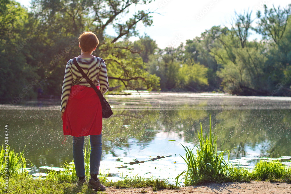 Rear view of senior woman standing on lake shore Rear view of senior woman standing on lake shore