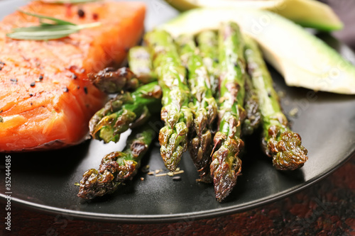Cooked asparagus with salmon on plate, closeup