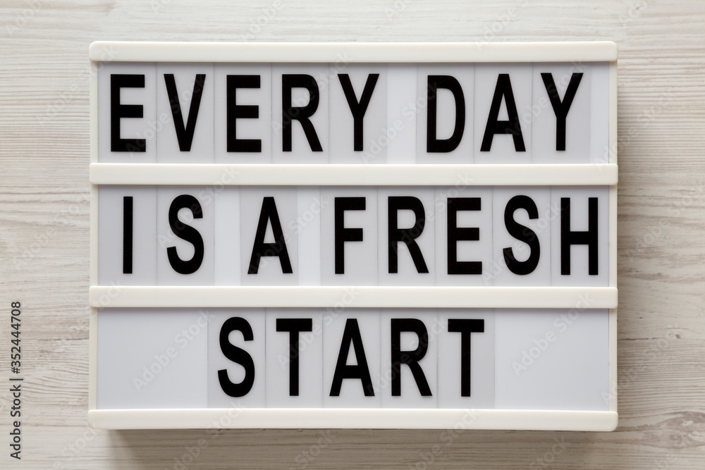 'Every day is a fresh start' words on a modern board on a white wooden background, top view. Overhead, from above, flat lay. 'Every day is a fresh start' words on a modern board on a white wooden background, top view. Overhead, from above, flat lay.