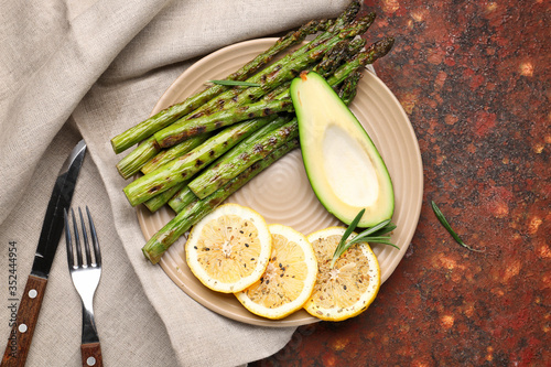 Cooked asparagus with avocado and lemon on color background