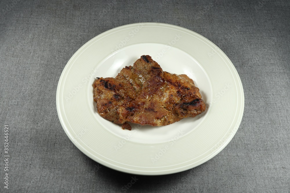 Traditional grilled pork steak on the plate. Famous roasted meat menu in Asia. High fat menu in restaurant. Traditional grilled pork steak on the plate. Famous roasted meat menu in Asia. High fat menu in restaurant.