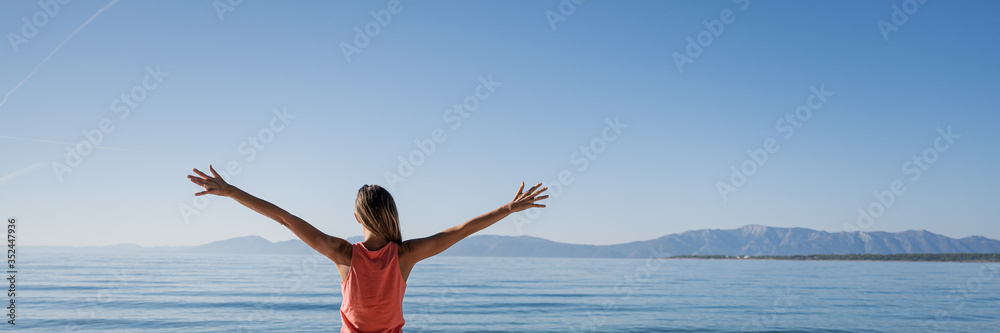 Young woman standing by the morning sea greeting the new day Young woman standing by the morning sea greeting the new day