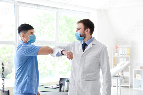 Doctors greeting each other in clinic. Concept of social distance