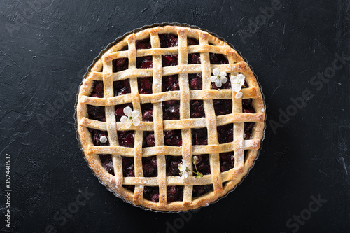 whole homemade cherry pie on a black background, view from above