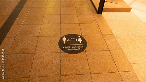 A social distance warning sign on the ground in a shopping mall.The mark was placed because of the coronavirus.(Hungarian:Kérjük,tartsanak távolságot!)